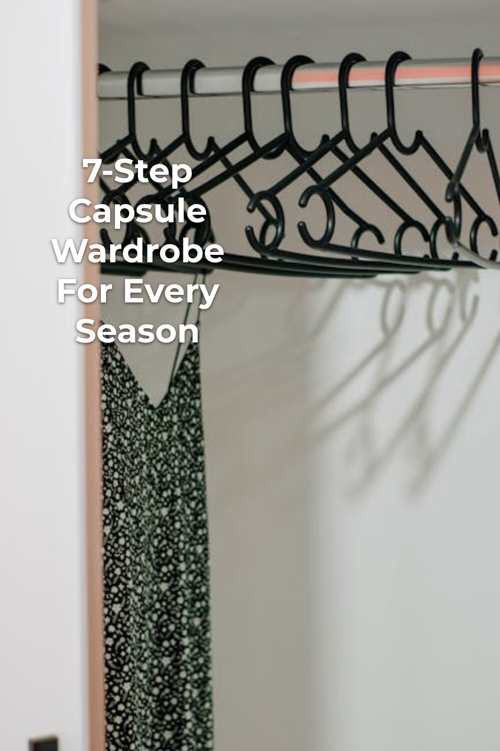 Closet hangers for a capsule wardrobe Black plastic hangers on a closet rod above a patterned dress, capsule wardrobe minimalist planning
