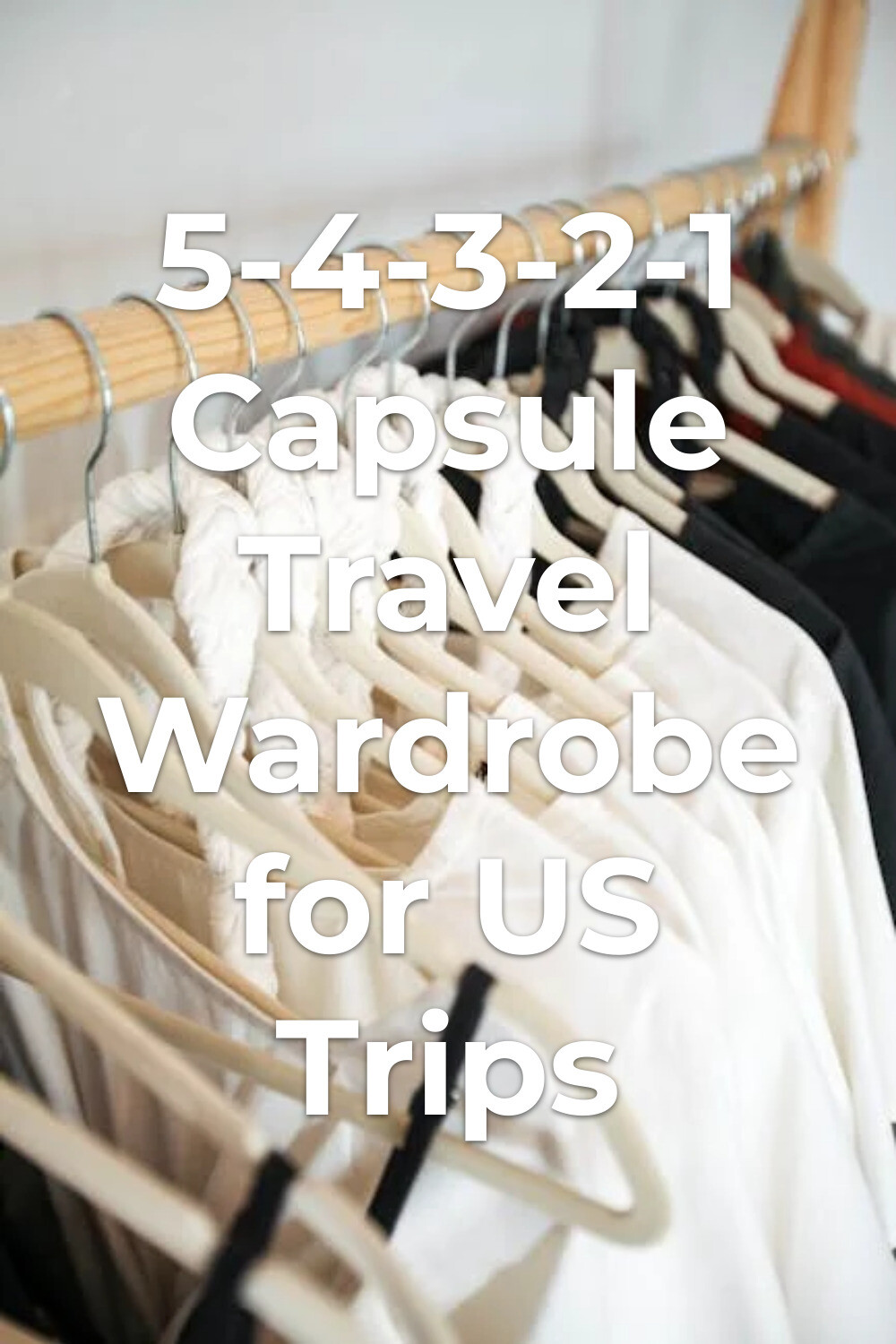 capsule travel wardrobe with black and white clothes on hangers on a wooden rack for minimalist packing
