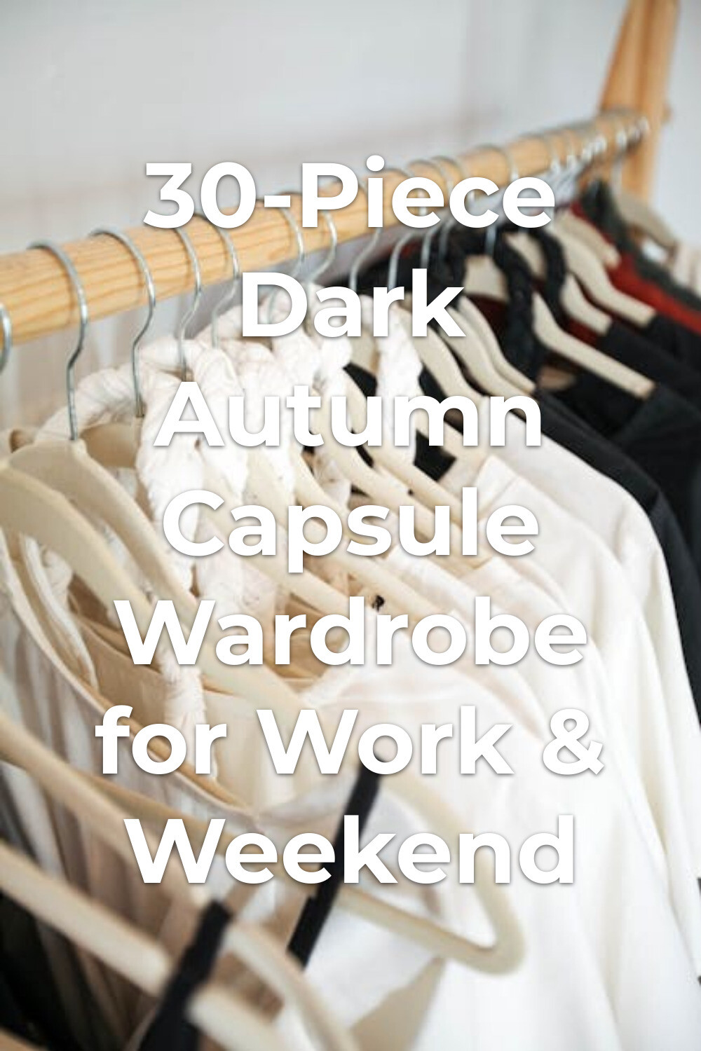 White and black shirts on hangers on a wooden rack for a dark autumn capsule wardrobe