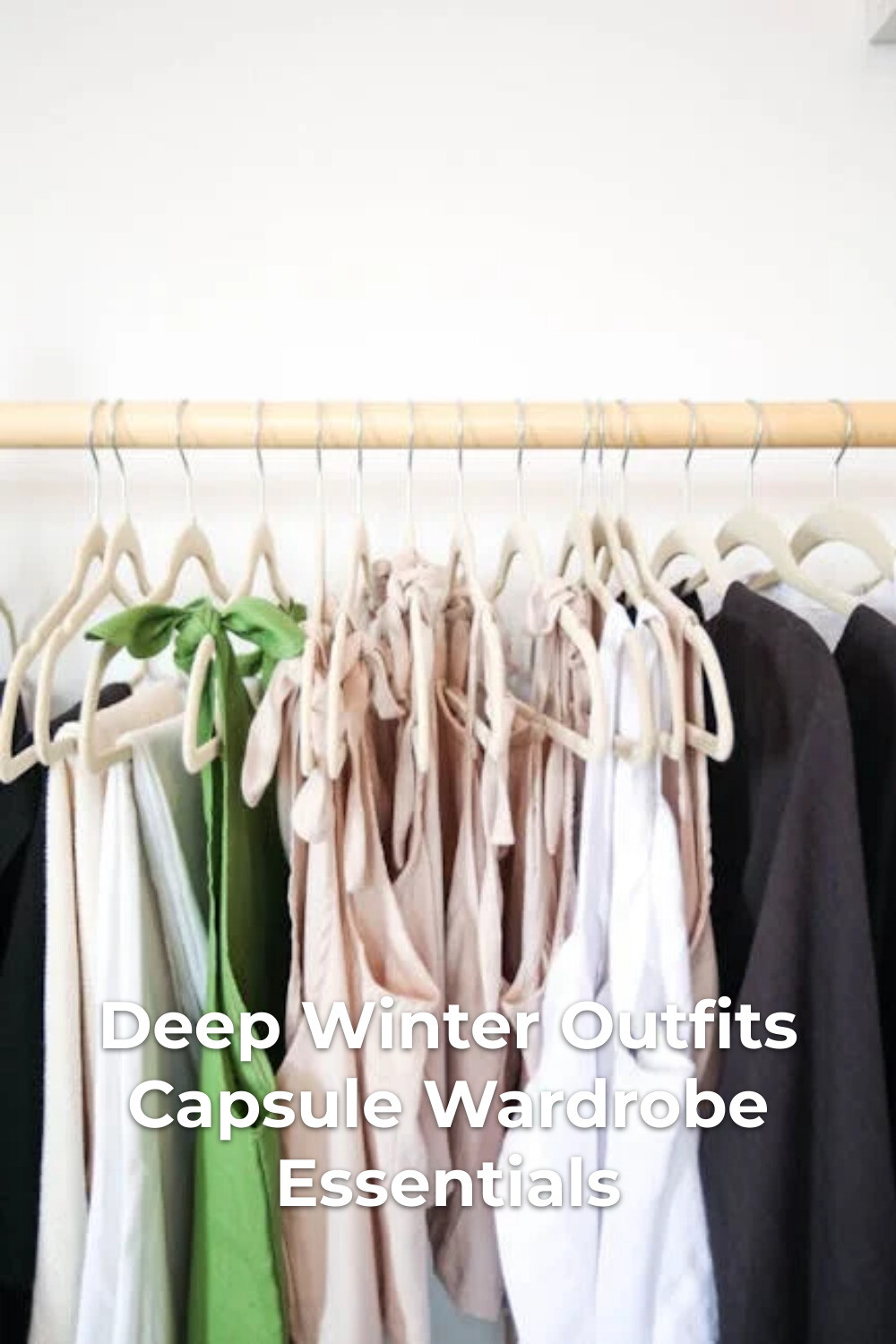 Deep winter outfits capsule wardrobe on minimalist clothing rack with shirts and dresses against a white wall
