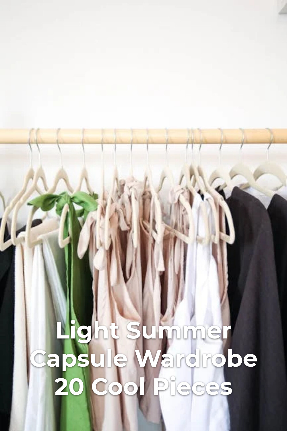 Light summer capsule wardrobe with colorful clothes on wooden hangers on a rack against a white wall