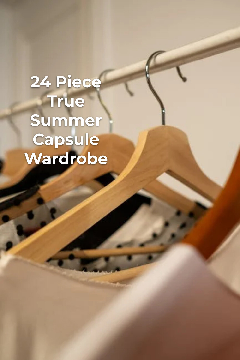 True Summer Capsule Wardrobe on Wooden Hangers True summer capsule wardrobe clothes on wooden hangers with light and black garments on a metal rail