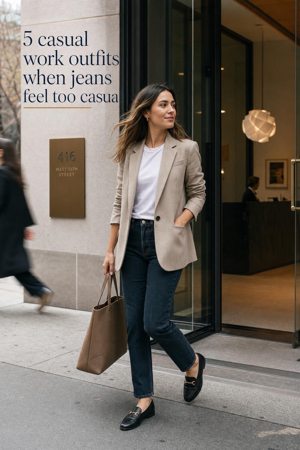 Casual work outfits inspiration with a woman in oatmeal blazer, white tee and dark jeans entering a modern office lobby